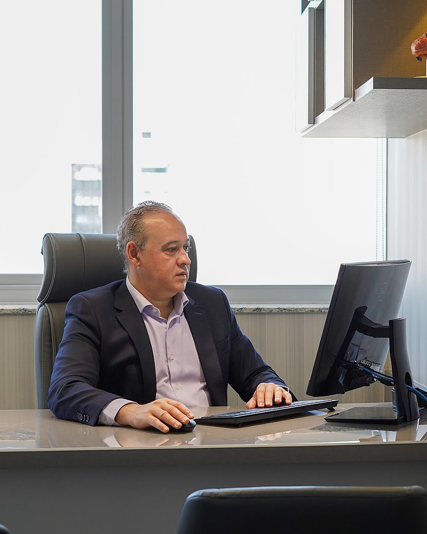 Dr. Vinicius concentrado, olhando pela janela do consultório.